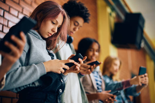 High school student and her friends using their phones in a hallway